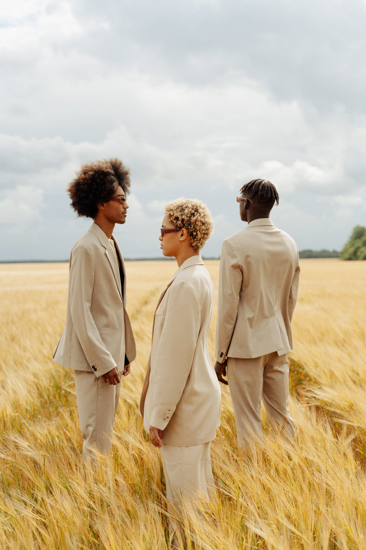 tre ragazzi in piedi in un campo di grano, vestiti di beige