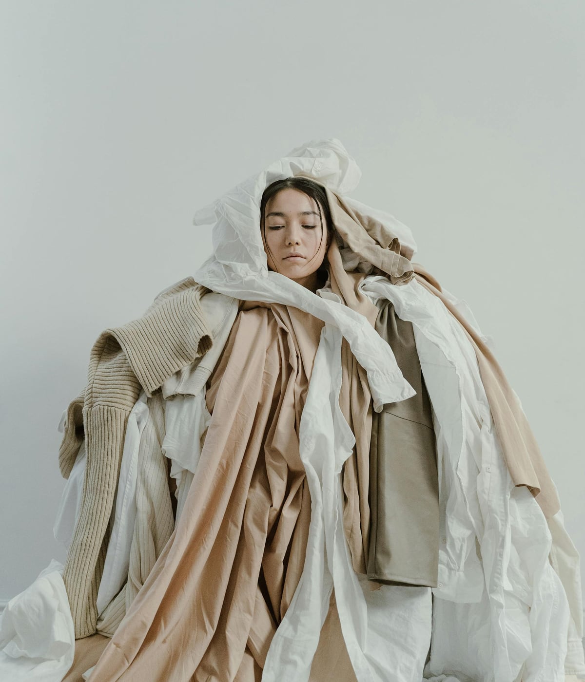 Woman surrounded by a cascade of garments, symbolizing a commitment to combating waste in fashion. With Temera’s RFID technology, each garment is tracked t